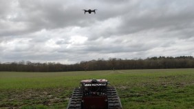 An N2Vision robot prototype in a field with a drone hovering above